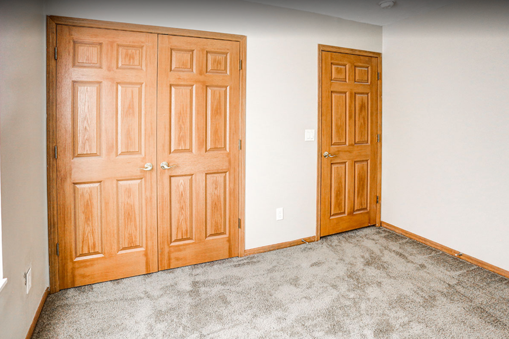 two wooden doors in a room with carpet and white walls