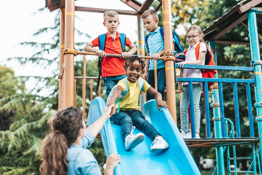 a group of children playing on a slide on a playground