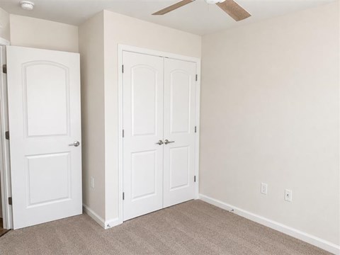 A room with two white doors and a ceiling fan.