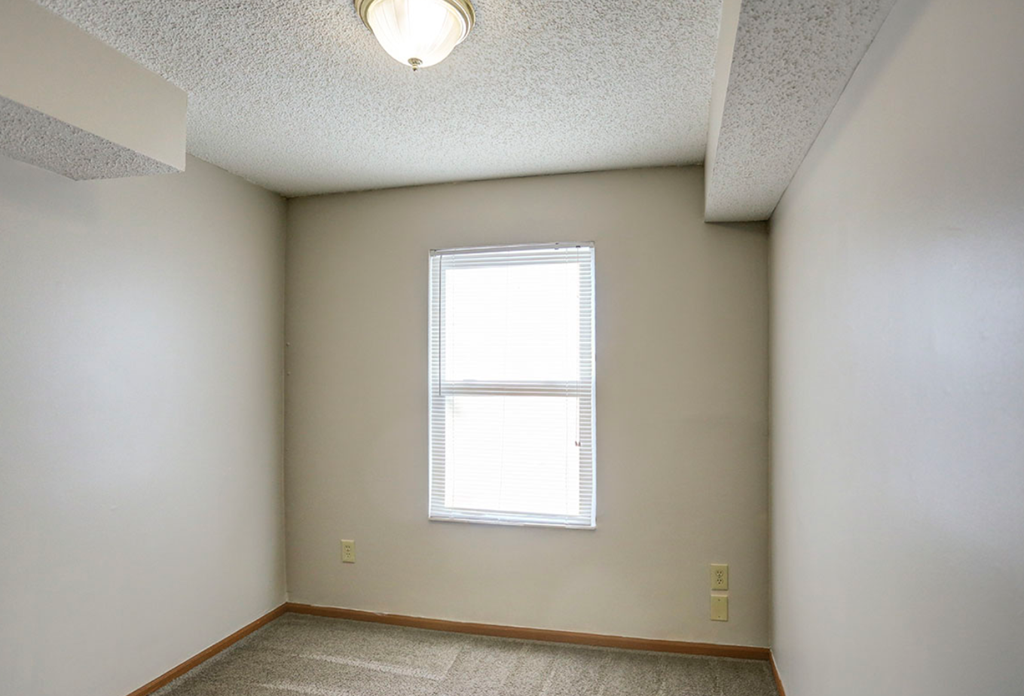 an empty room with a window and white walls