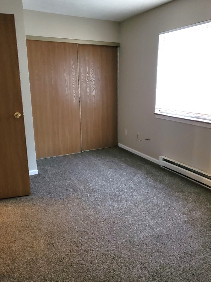 a bedroom with a carpeted floor and a closet