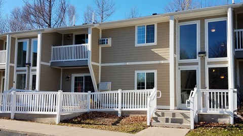 a tan house with a white fence in front of it