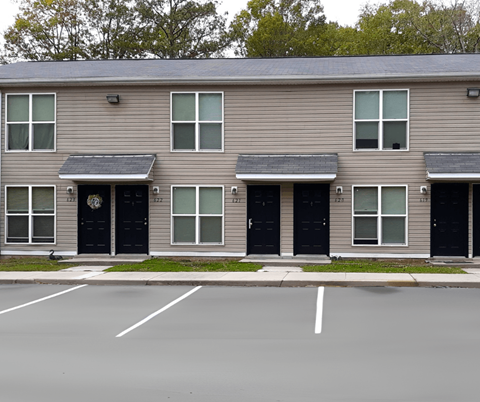 an apartment building with black doors and a parking lot