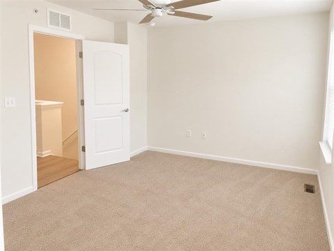 A room with a ceiling fan and carpeted floor.