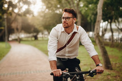 A man in a white shirt and suspenders is riding a bicycle on a path.