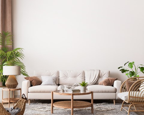 A living room with a white sofa, a wooden coffee table, and a wicker chair.