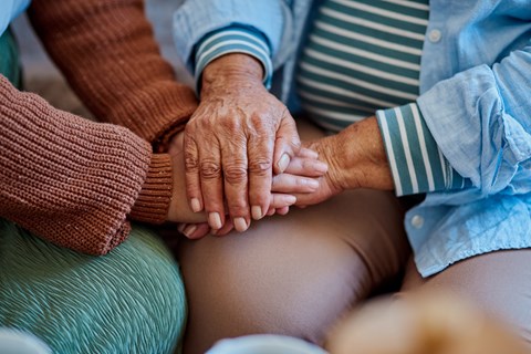Two hands clasped together in the center of a group of people.