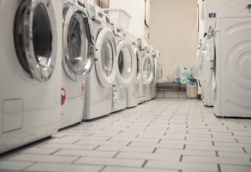 A row of white front load washing machines in a laundromat.
