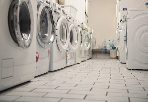 A row of white front load washing machines in a laundromat.