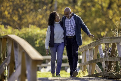 A man and a woman are walking on a bridge.