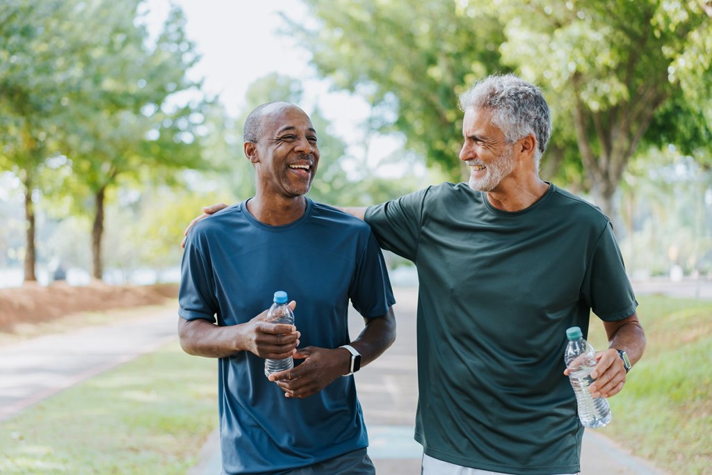 Two men are walking and talking in a park.