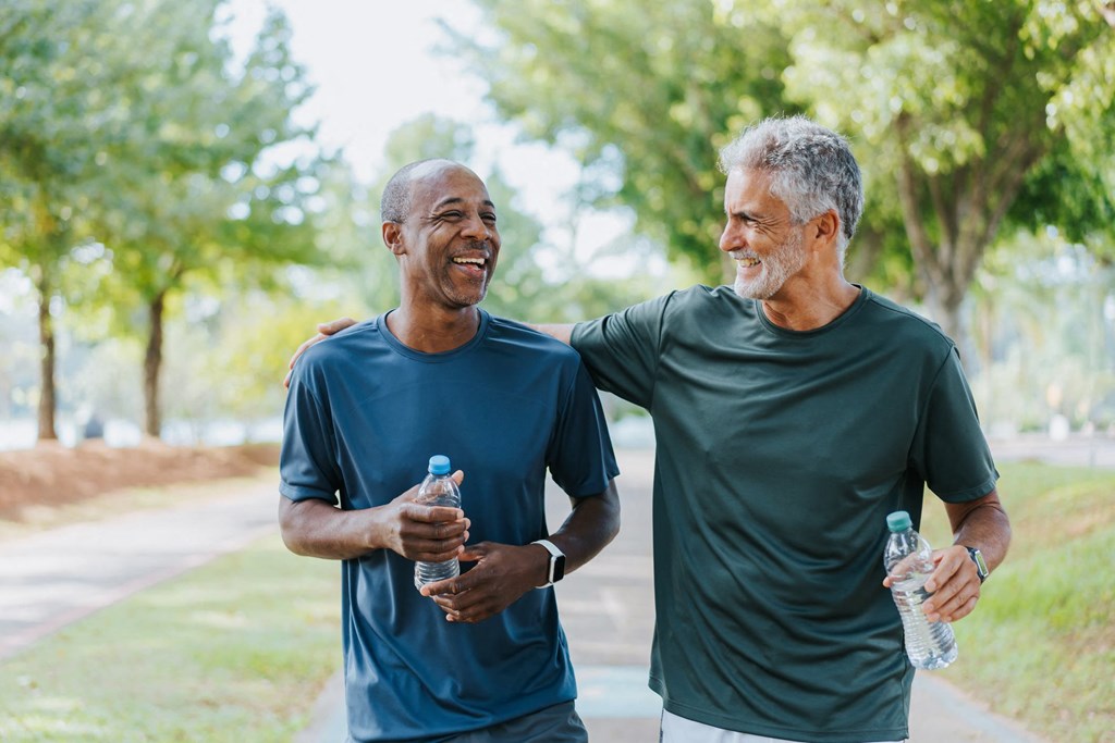 Two men are walking and talking in a park.