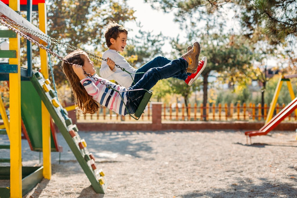 A child is swinging on a swing at a playground.