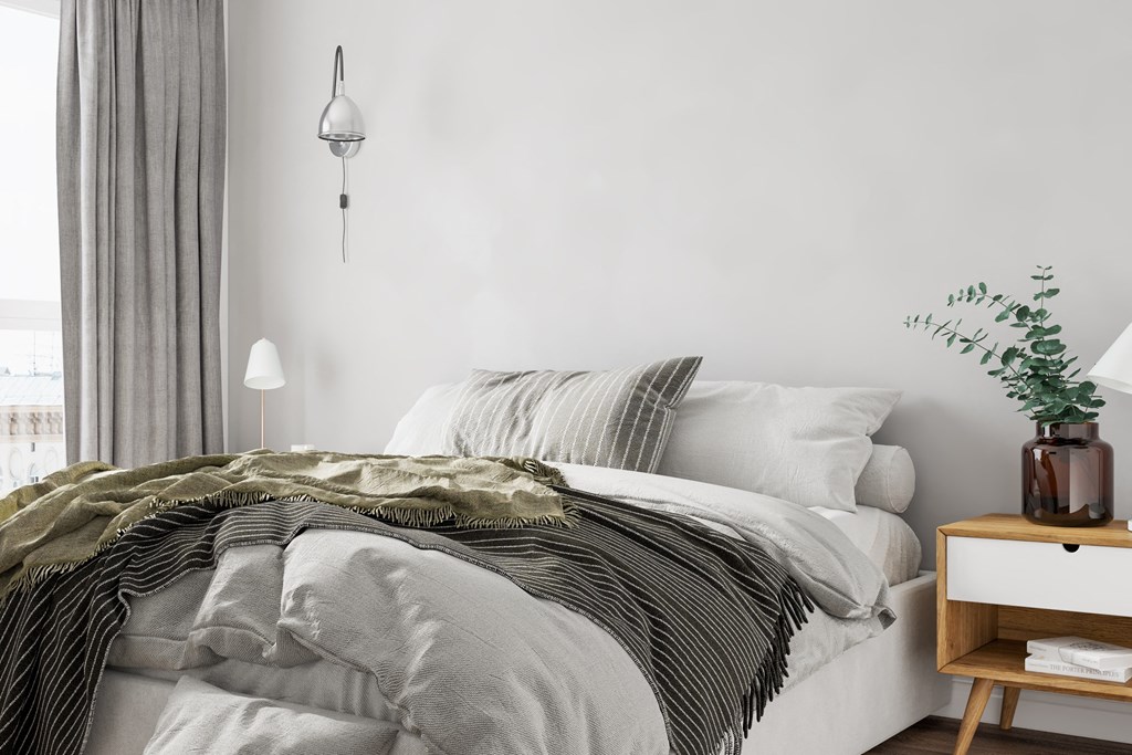 A bed with a white comforter and a green striped blanket.