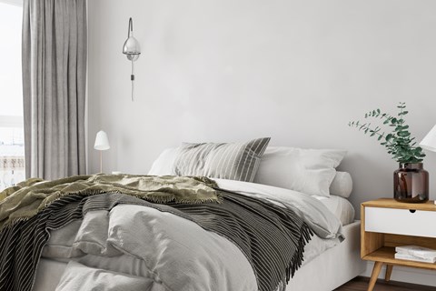 A bed with a white comforter and a green striped blanket.