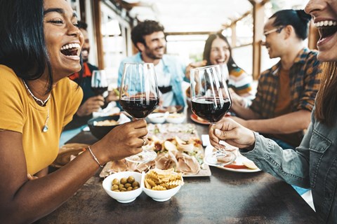 A group of people are enjoying a meal and drinks together at a table.