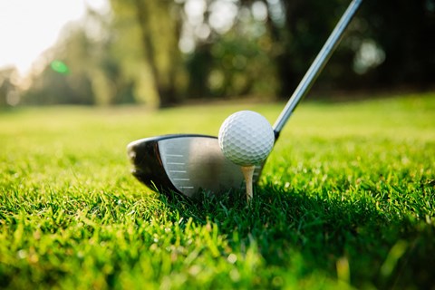 A golf ball is on a tee ready to be hit.