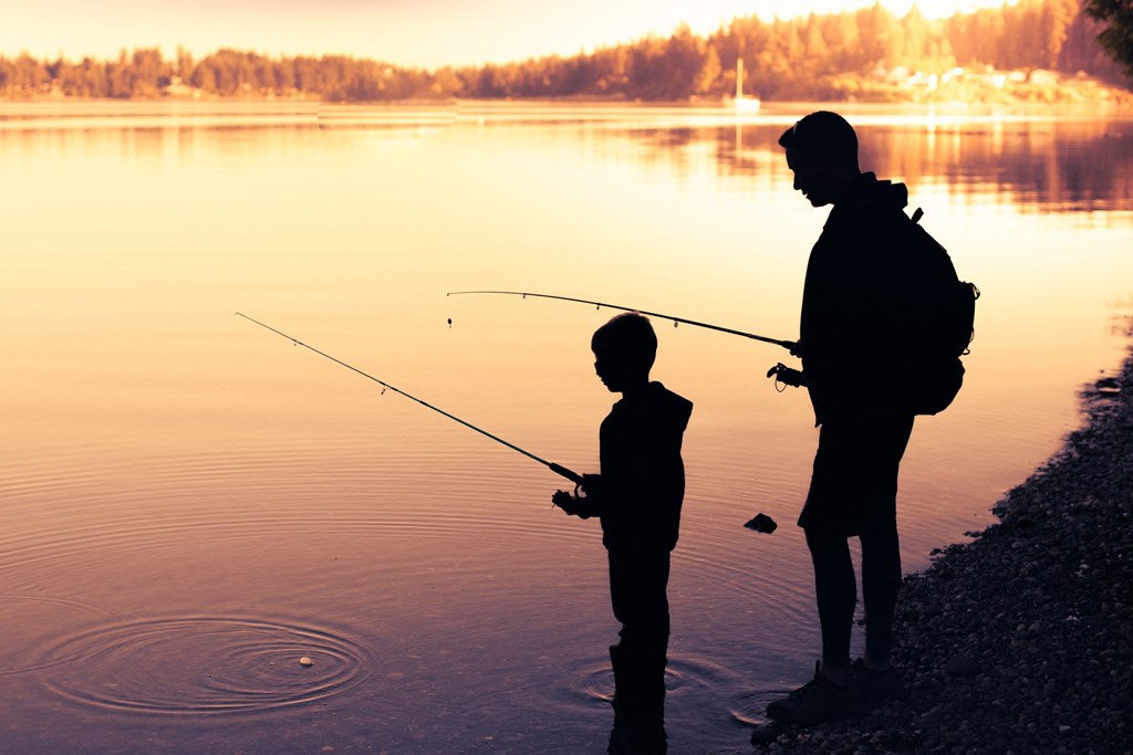 A man and a child are fishing by the water.