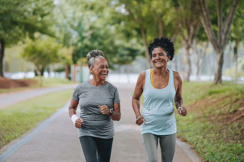 Two women jogging on a path in a park.