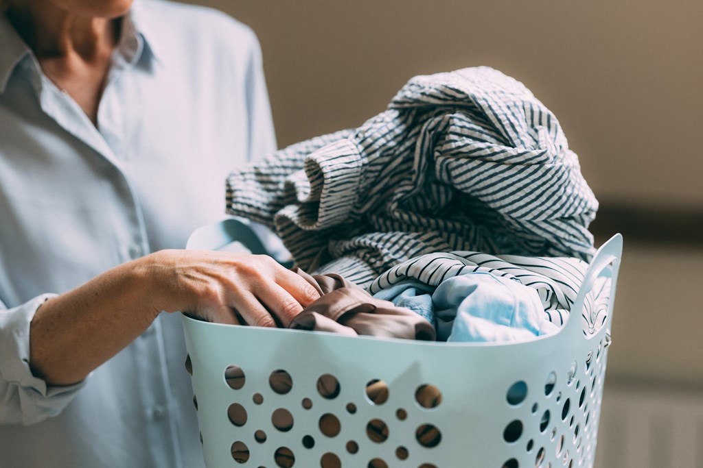 A person is holding a laundry basket full of clothes.