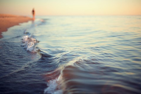 A person is walking on the beach near the water.