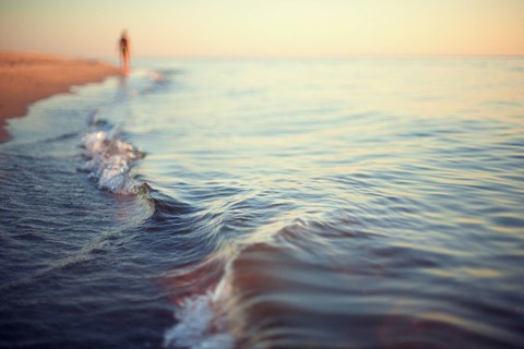 A person is walking on the beach near the water.
