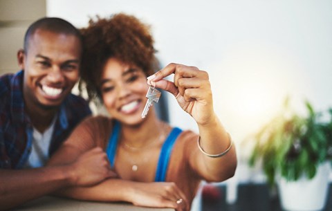 A man and woman are smiling and holding up a small object.