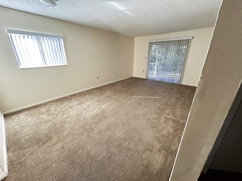 A room with a carpeted floor and a window with blinds.