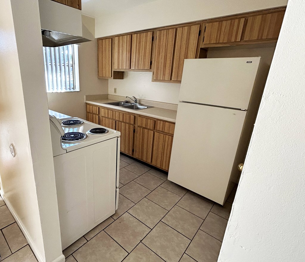 A white refrigerator is in a kitchen with wooden cabinets.