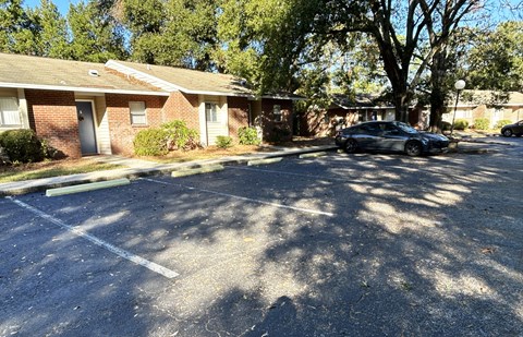 A black car is parked in a parking lot in front of a brick building.