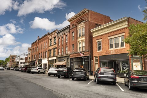 Cars parked on the side of a street in front of a row of buildings.