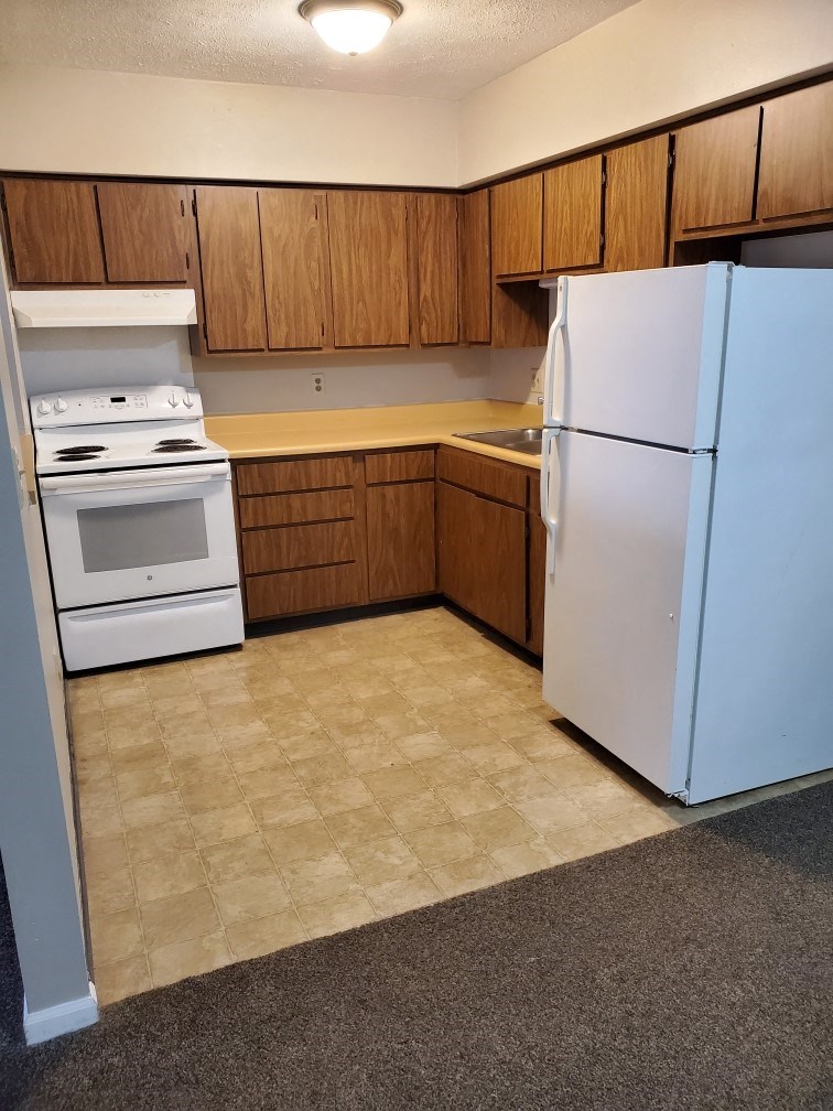 an empty kitchen with a white refrigerator and stove