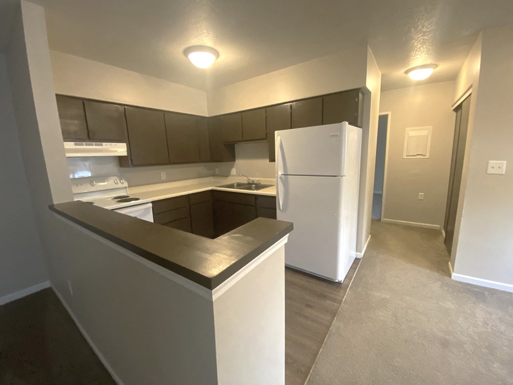 a kitchen with white appliances and dark cabinets and a white refrigerator