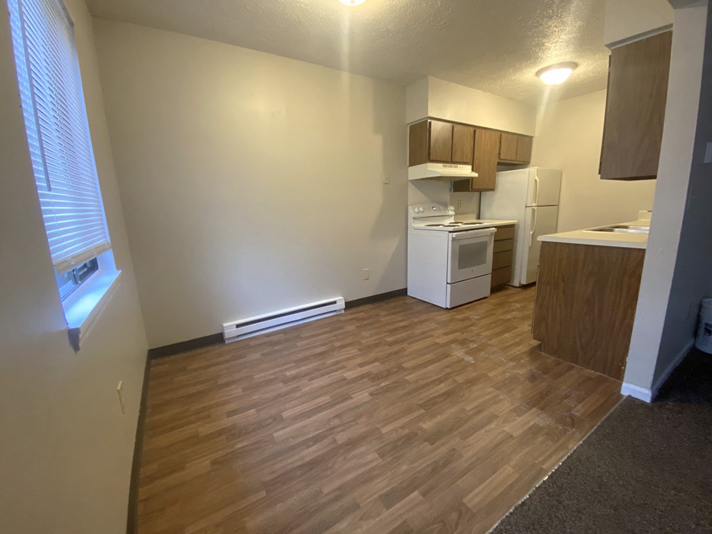 an empty room with a kitchen and a wooden floor