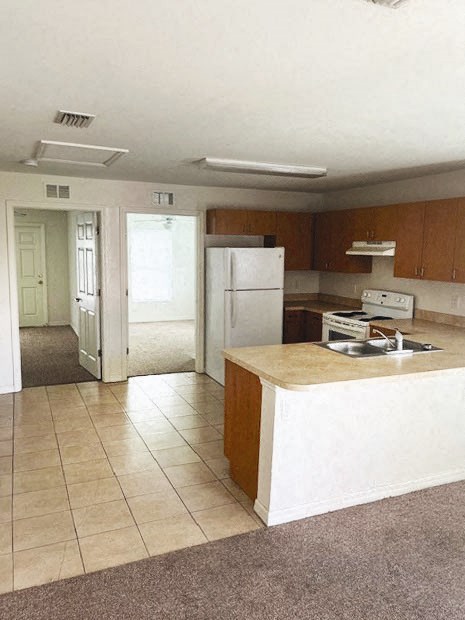 an empty kitchen with a sink and a refrigerator