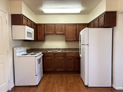 A kitchen with white appliances and brown cabinets.