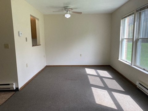 an empty room with a ceiling fan and two windows