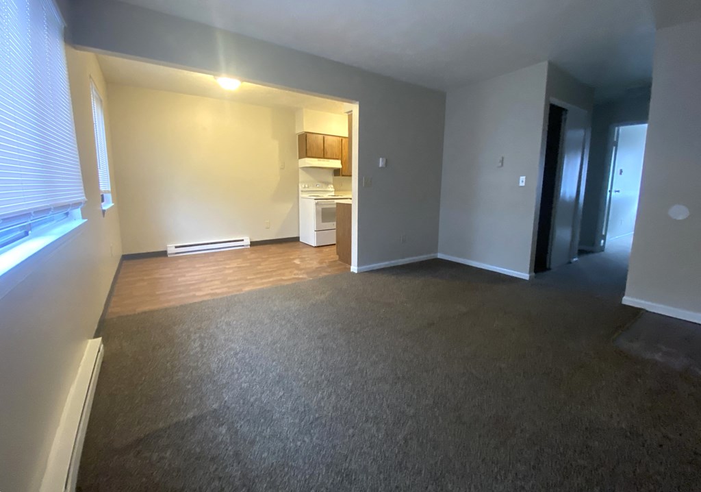 an empty living room with a large window and wood flooring