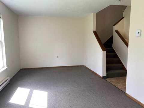 an empty living room with a staircase in the corner