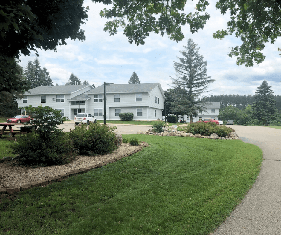 the view of a large white building with a driveway and a lawn