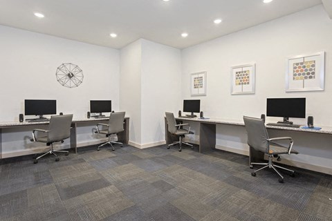 a room with three desks with computers and chairs