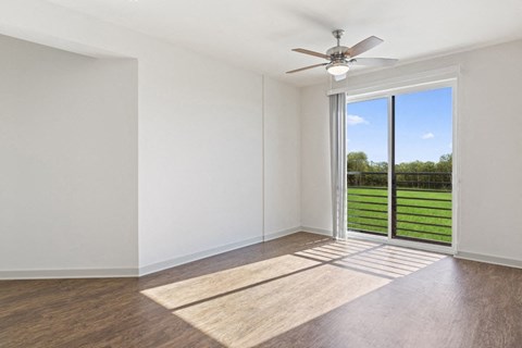 an empty living room with a sliding glass door to a yard