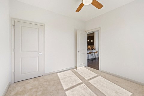 an empty living room with two doors and a ceiling fan