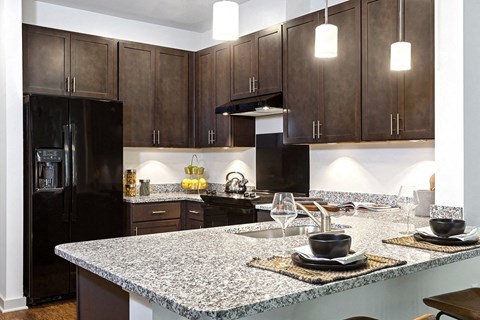 a kitchen with granite counter tops and dark wood cabinets