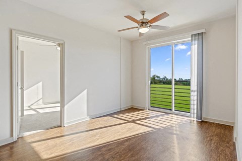 an empty living room with a ceiling fan and a window