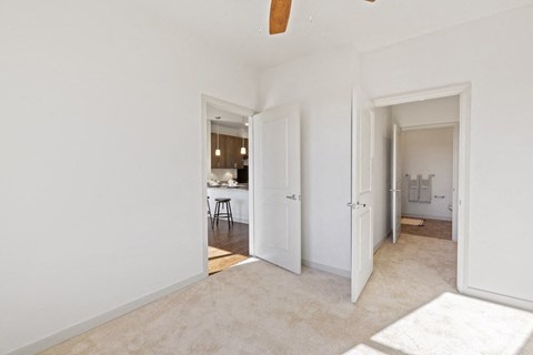 a living room with two doors and a hallway to a kitchen