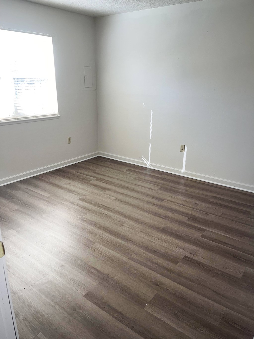 A room with wooden flooring and a window.