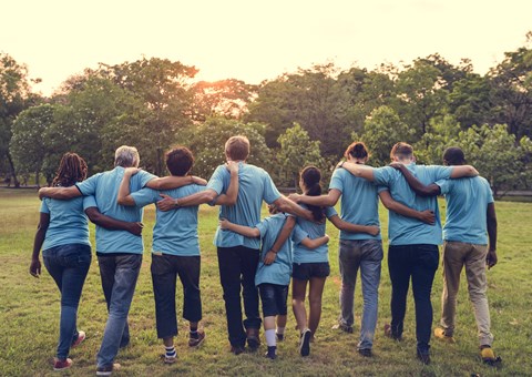a group of people wearing blue shirts walking in a park