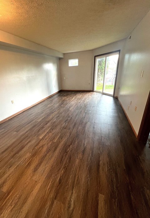 an empty living room with wooden floors and a window