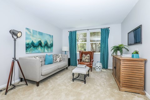 A living room with a couch, chair, and a painting on the wall.
